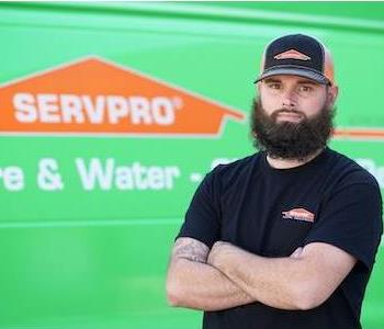 Young man with a brown eyes and hair wearing a SERVPRO ball cap and a serious expression standing by a SERVPRO truck