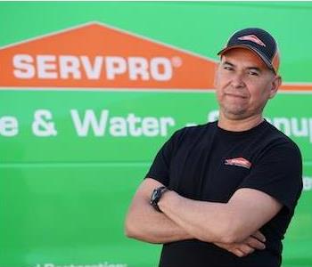 Middle aged, clean shaven man in ball cap and SERVPRO T-shirt standing next to a SERVPRO truck